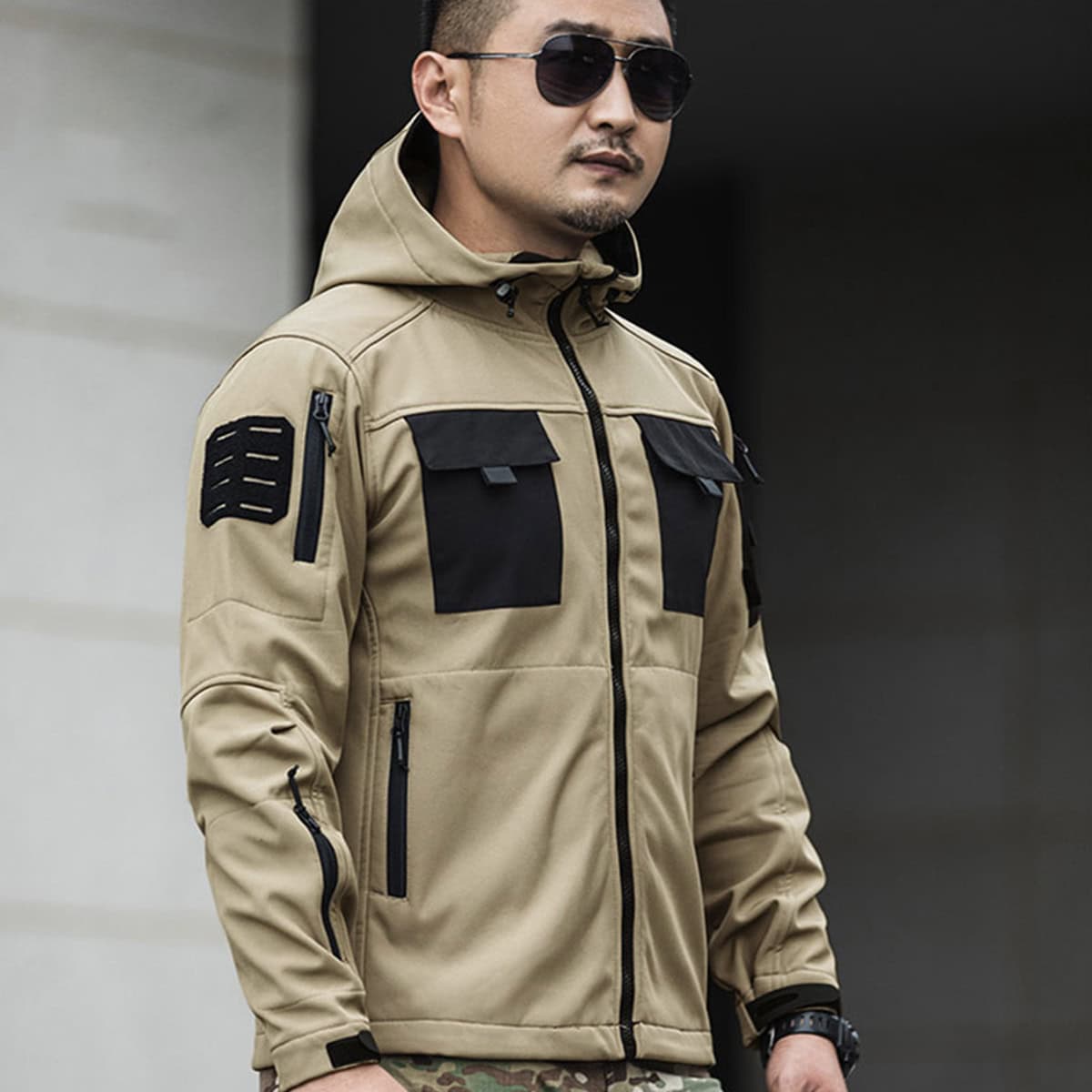 A professional wearing the khaki Onken Beetle fleece lined tactical jacket, demonstrating its ergonomic fit and compatibility with field gear like backpacks.