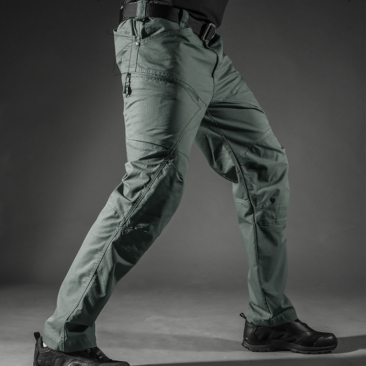 Operator wearing the grey Strider stretch tactical pants in a dynamic pose, demonstrating the superior freedom of movement from the 4-way stretch fabric.