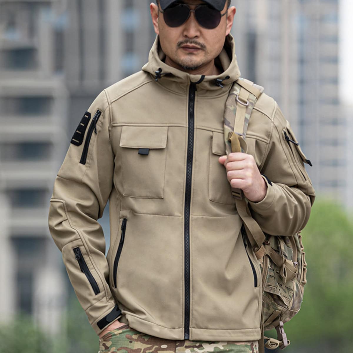 A professional wearing the khaki Onken Beetle fleece lined tactical jacket, demonstrating its ergonomic fit and compatibility with field gear like backpacks.