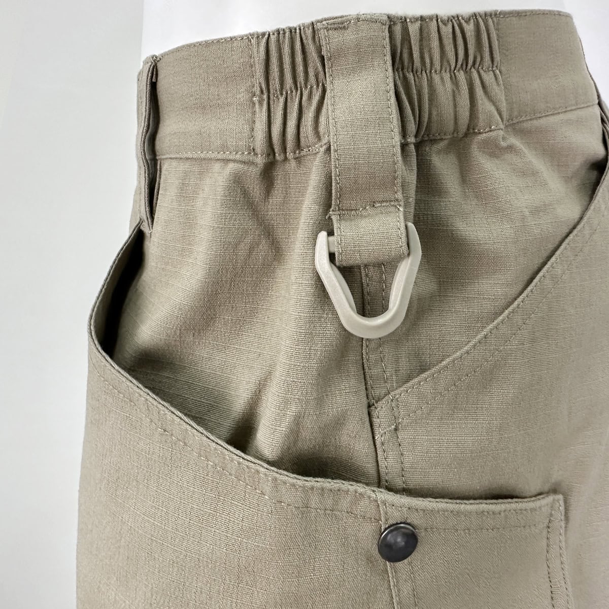 Close-up of the comfortable elastic waistband and durable D-ring on the Strider stretch tactical pants, designed for all-day wear with a duty belt.