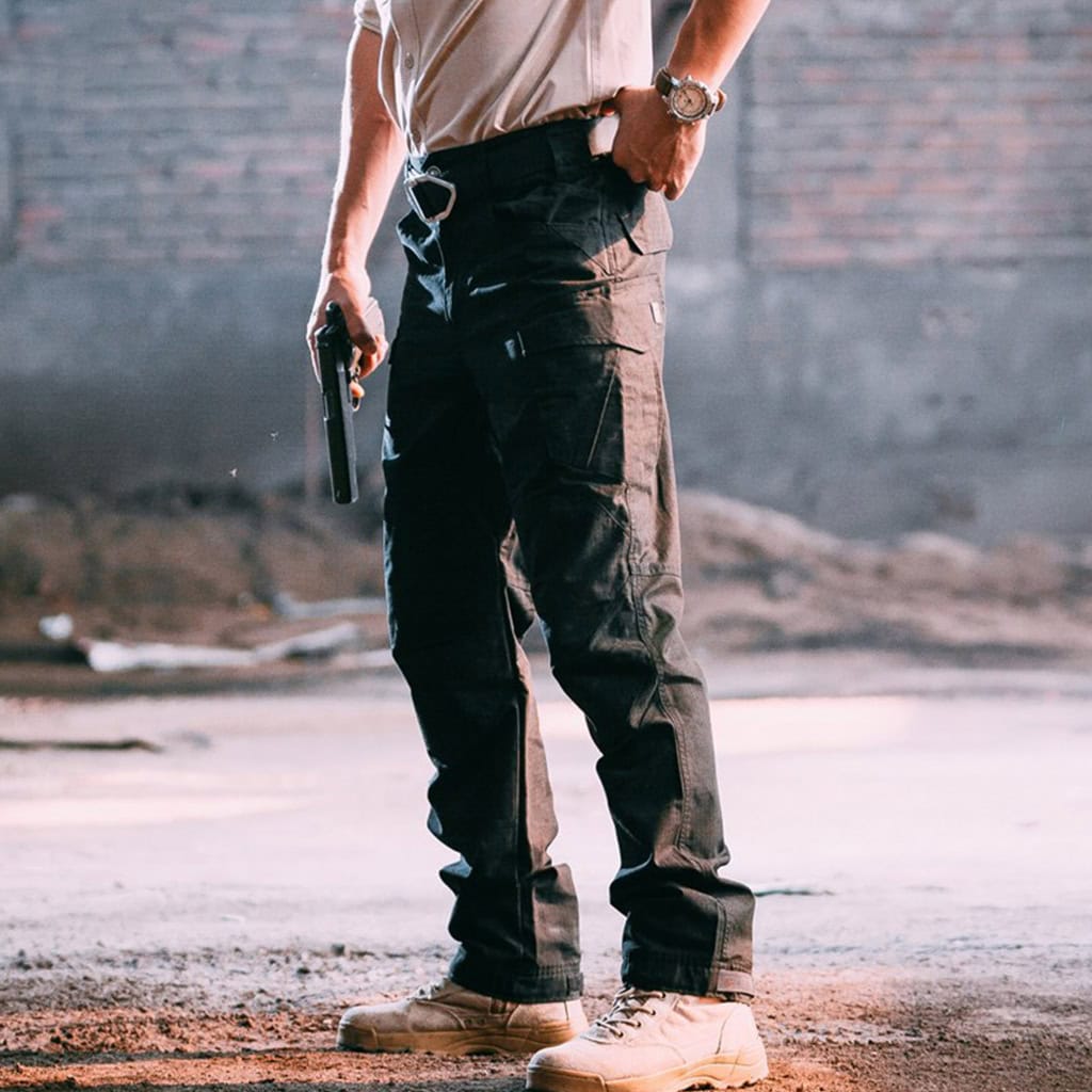 A professional wearing the black water-resistant tactical pants, demonstrating the clean profile and accessible cargo pocket design.