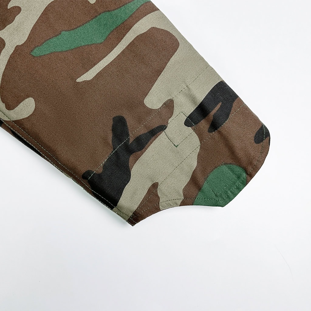 Detail of the buttoned shoulder tab (epaulet) on the Woodland Camo Tactical Jacket, used for displaying rank insignia or securing gear straps.