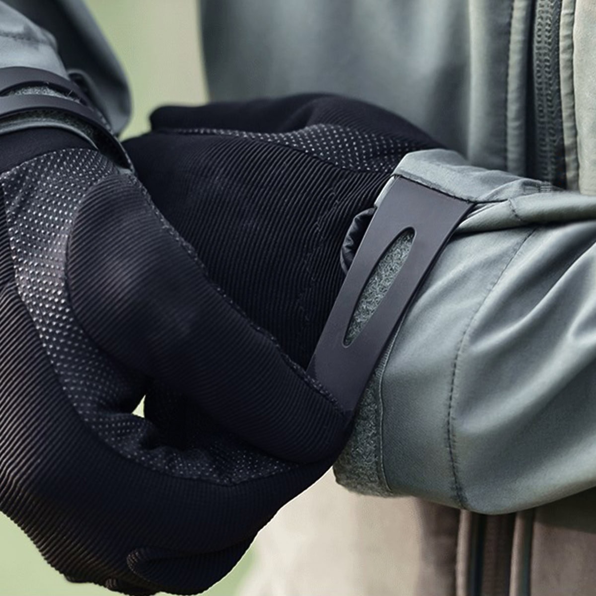 Detail of the adjustable velcro cuff on the Onken tactical jacket, shown fitting securely over a tactical glove to seal out wind and rain.