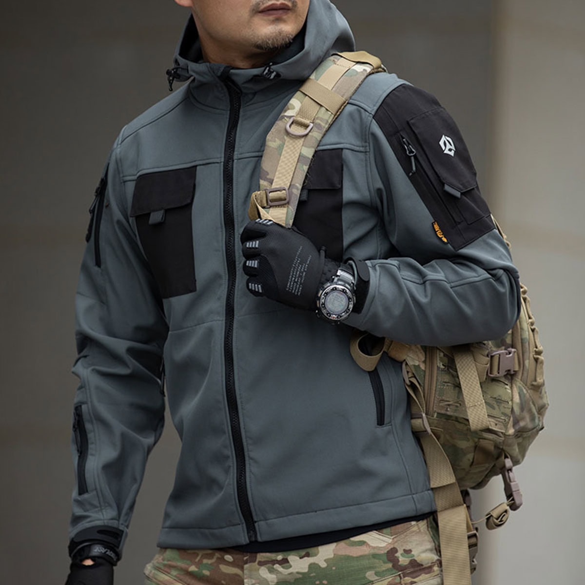 Operator wearing the grey Onken Beetle fleece lined tactical jacket, showing the arm pocket detail and seamless integration with tactical gloves and a backpack.