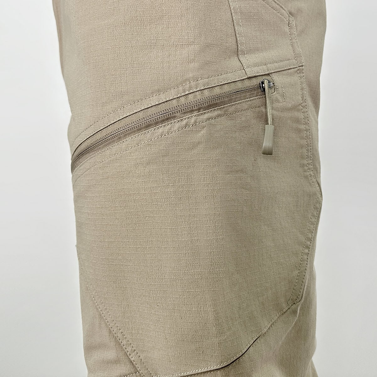 Detail of the articulated knee and zippered low-profile cargo pocket on the Strider stretch tactical pants, engineered for durability and secure gear storage.
