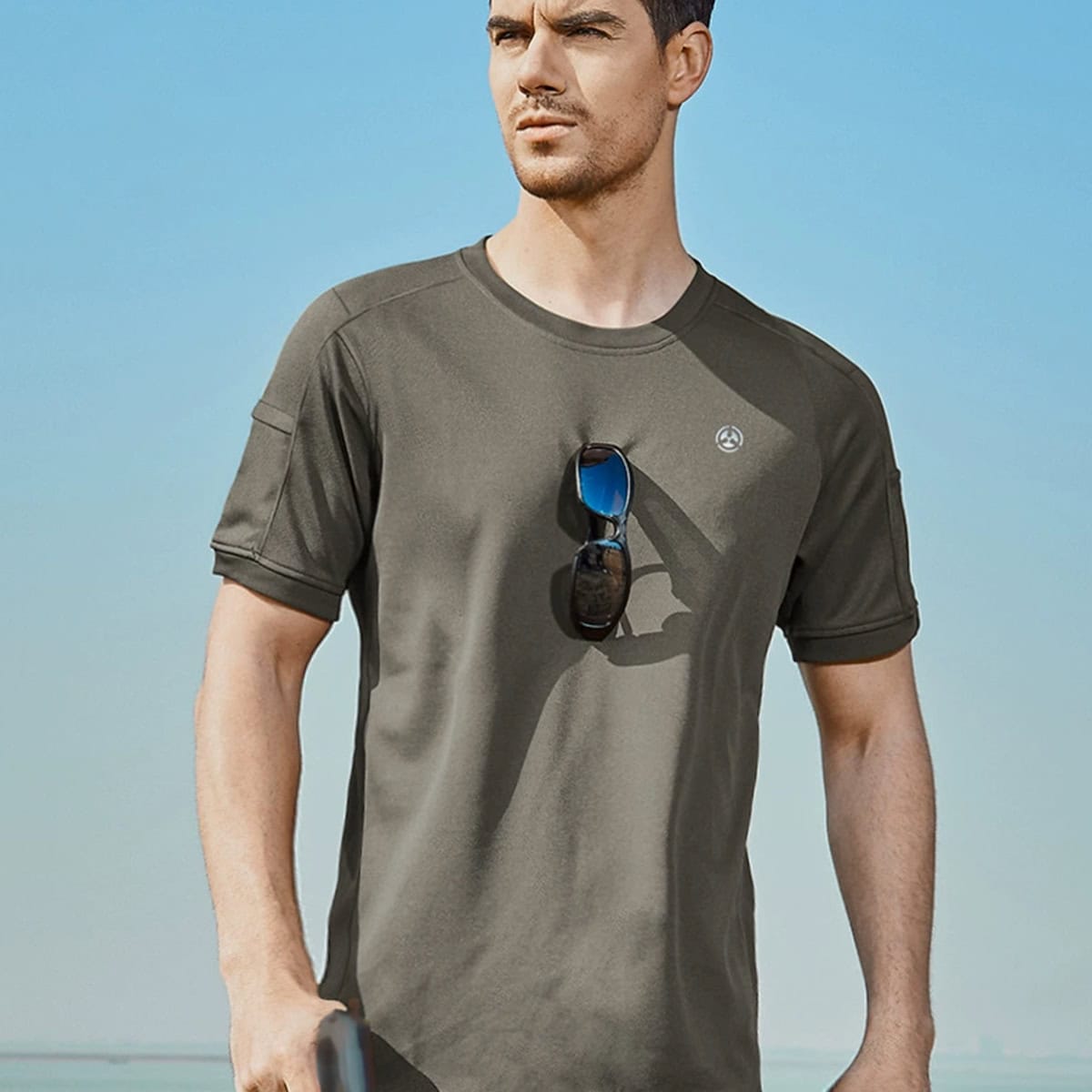 A professional wearing the olive green CMAX moisture-wicking tactical t-shirt, demonstrating its athletic fit and breathability for outdoor use.
