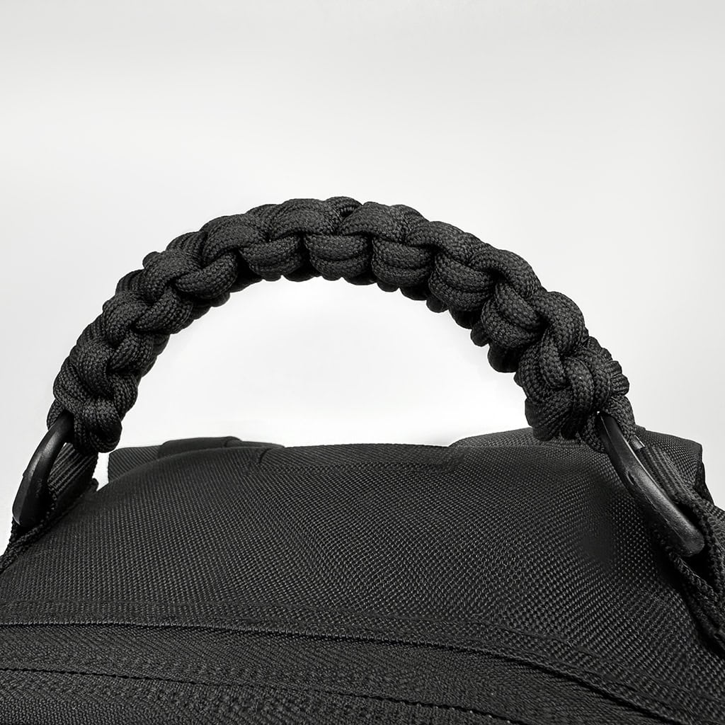 Detail of the Pathfinder backpack's heavy-duty, paracord-braided grab handle, engineered for extreme load-bearing capacity.