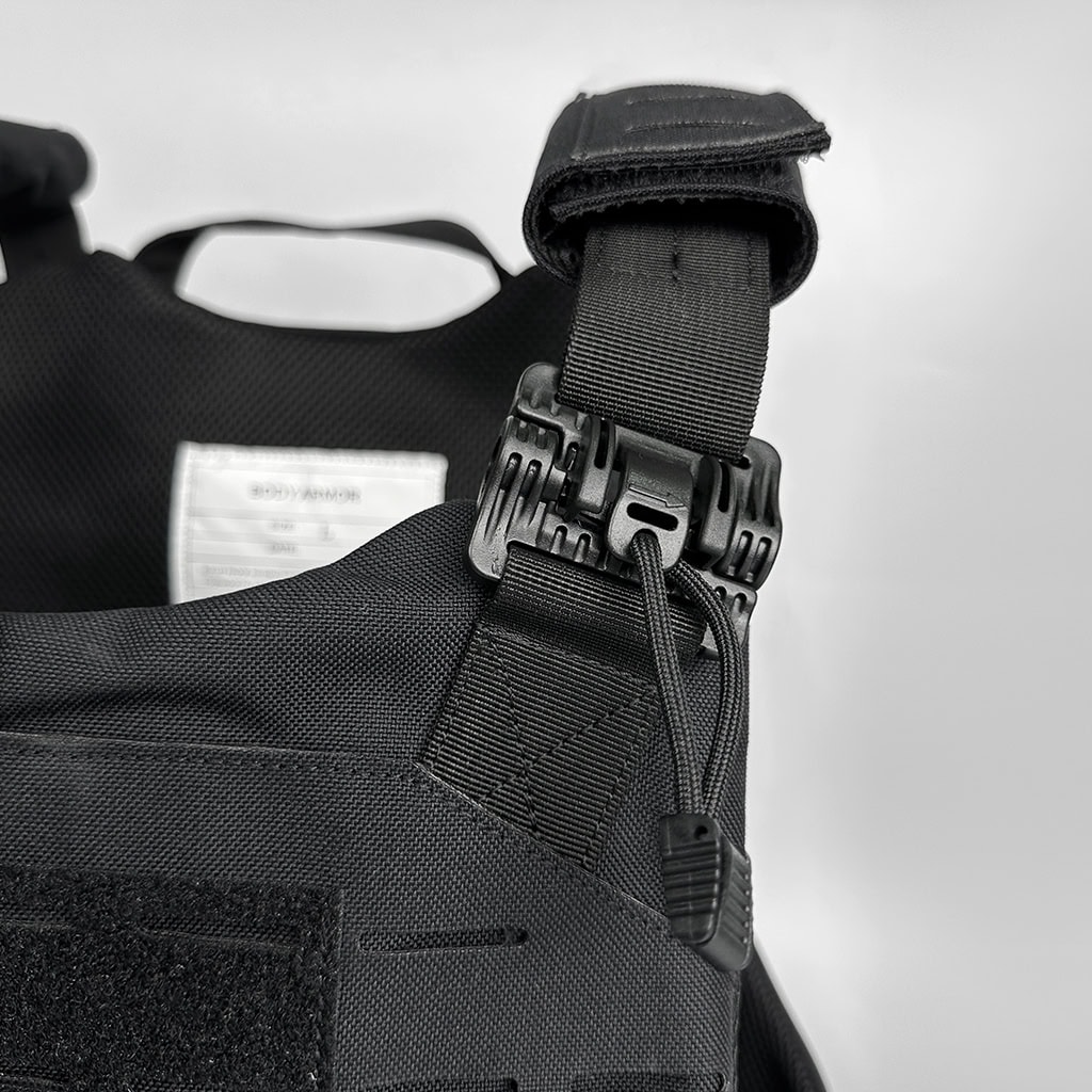 Close-up of the shoulder quick-release buckle on the "Spartan" plate carrier, a critical safety feature for emergency doffing.