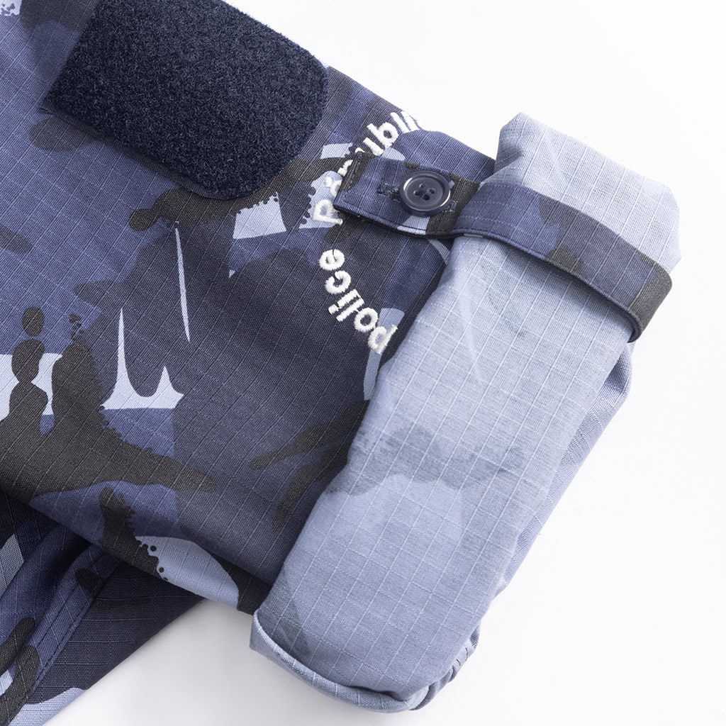 Close-up of the adjustable sleeve cuff on the blue camo uniform, showing a "Police" marking and velcro patch.
