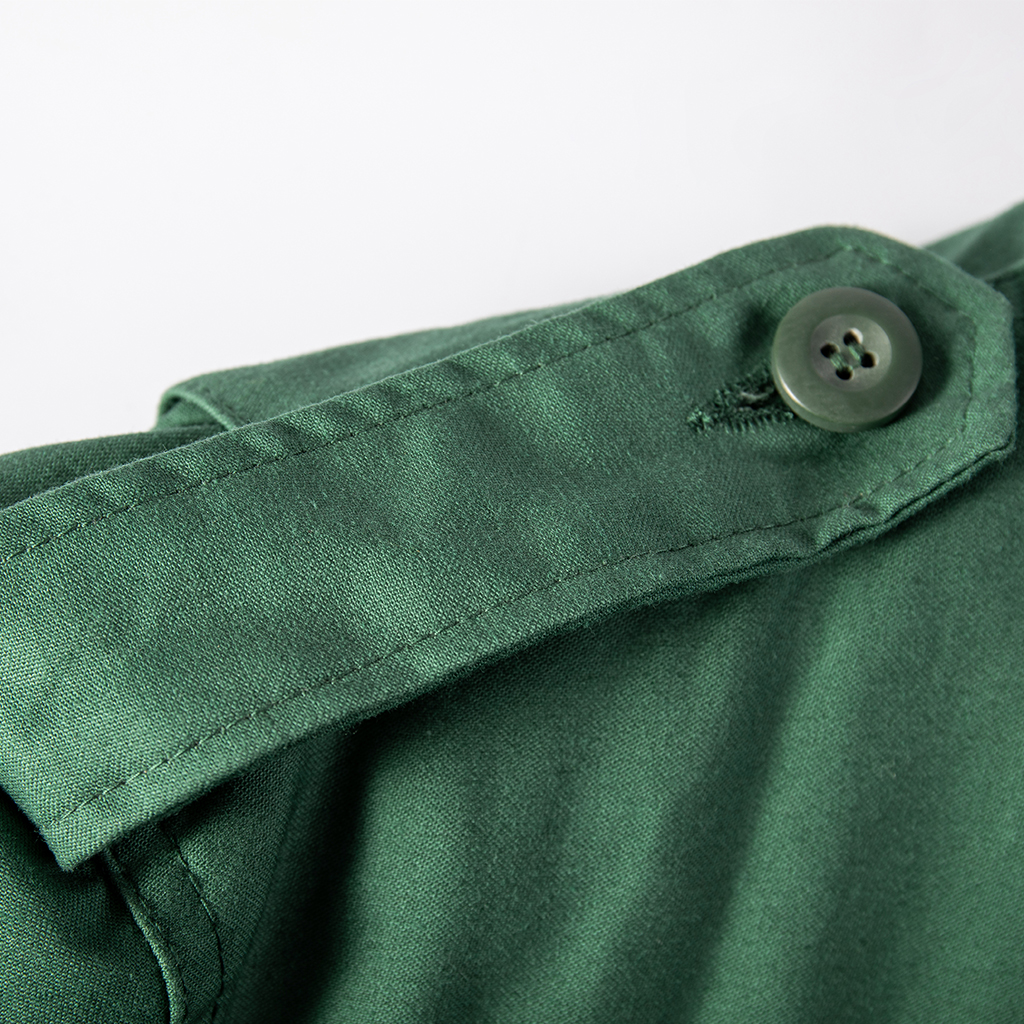 Close-up of the buttoned shoulder epaulette on the custom olive green M65 field jacket.