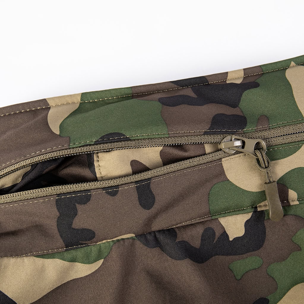 Close-up of a zippered chest pocket on the custom woodland camo softshell tactical jacket.