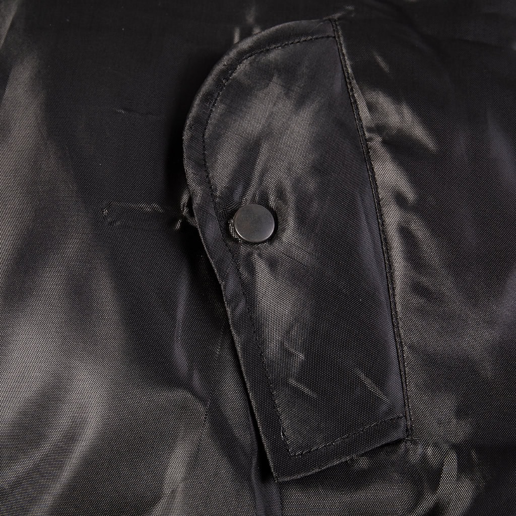 Close-up of the snap-closure front slash pocket on the custom black MA-1 flight jacket.