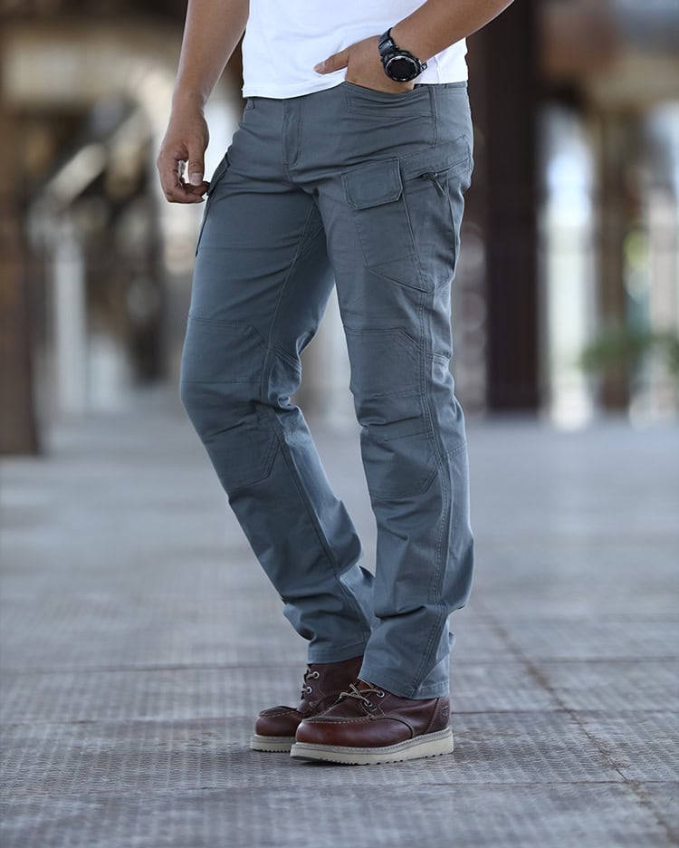 A man wearing the custom ripstop IX7 tactical pants in Grey Green, showing the side profile with cargo pockets.