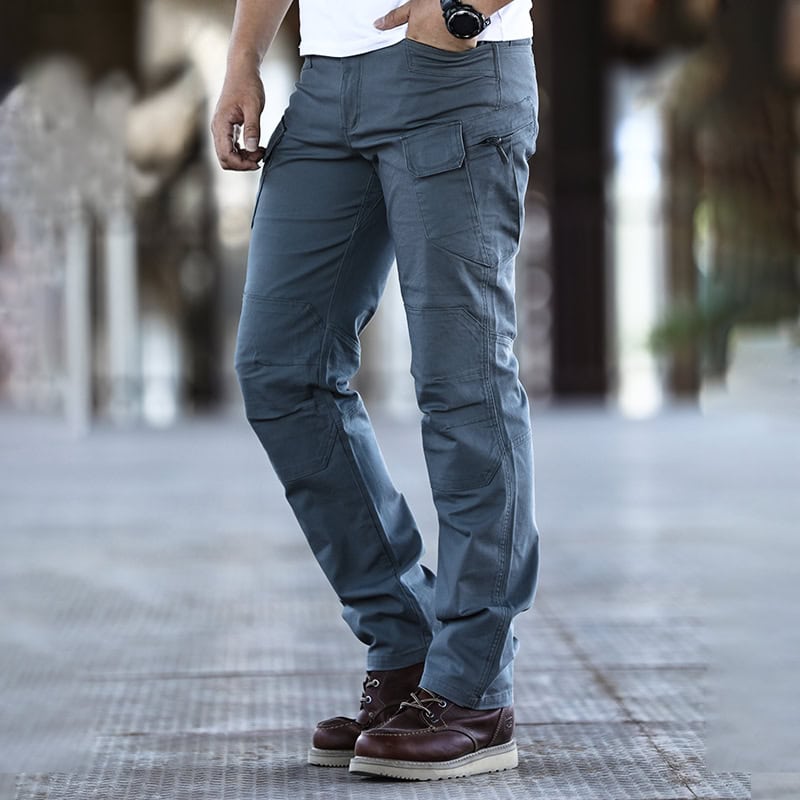 A man wearing the custom ripstop IX7 tactical pants in Grey Green, showing the side profile with cargo pockets.