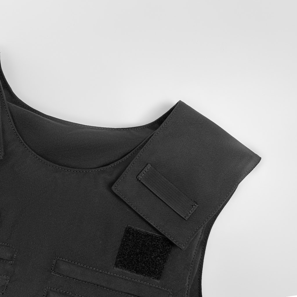 Close-up of the adjustable shoulder strap and velcro panel on the custom black concealable body armor vest carrier.