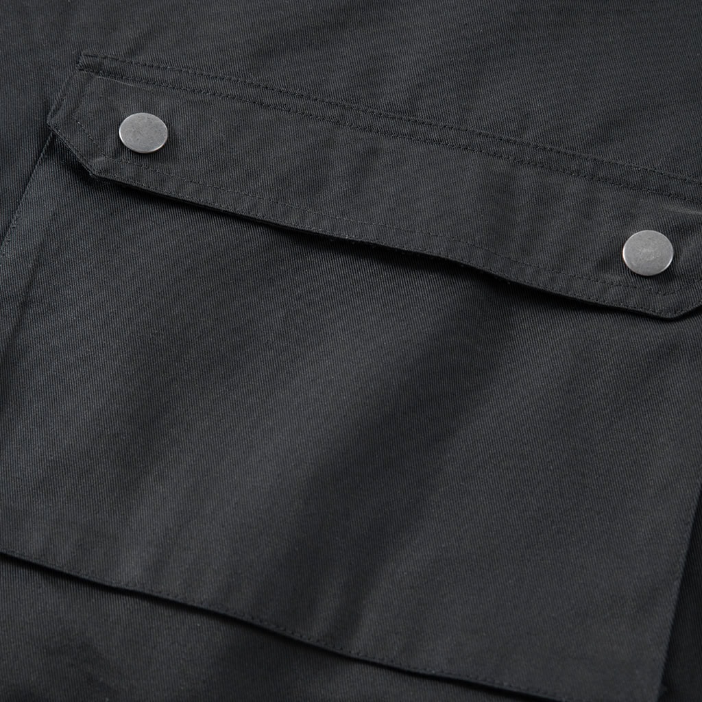 Detail of a large, snap-closure waist pocket on the custom black multi-pocket tactical vest.