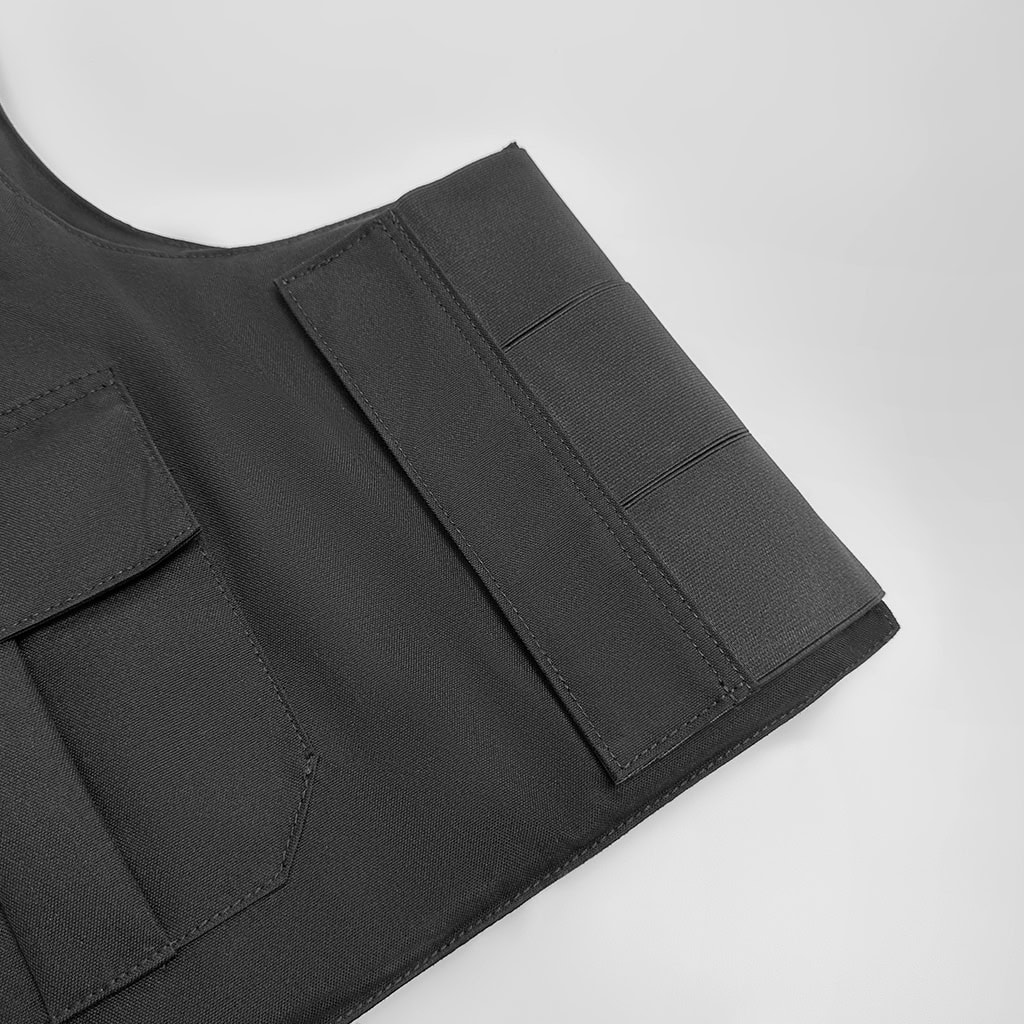 Detail of the front utility pockets on the custom black concealable body armor vest carrier.