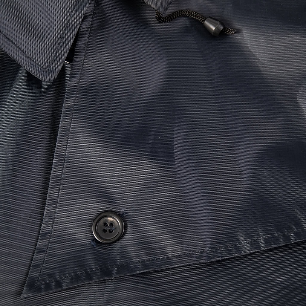 Detail of a button closure on the shoulder epaulette of the custom navy blue waterproof trench coat.