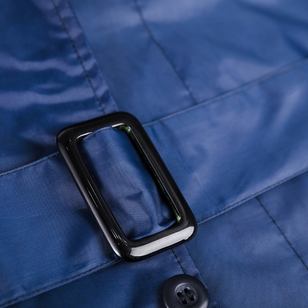 Detail of the adjustable waist belt and buckle on the custom navy blue waterproof long raincoat.