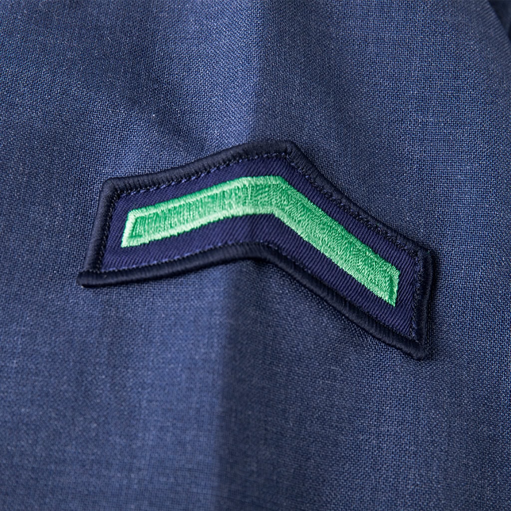 Detail of an embroidered rank insignia patch on the sleeve of the custom navy wool blend uniform shirt.