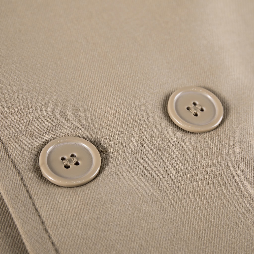 Close-up of the high-end custom buttons on the double-breasted front of the khaki military officer trench coat.