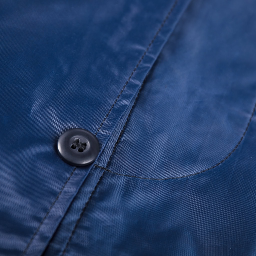 Close-up of a high-end custom button on the front of the navy blue waterproof long raincoat.