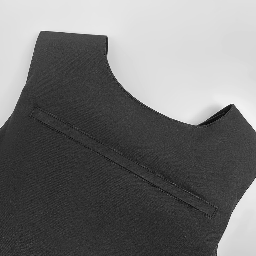 Close-up of the zippered pocket on the back of the custom black concealable body armor vest carrier.
