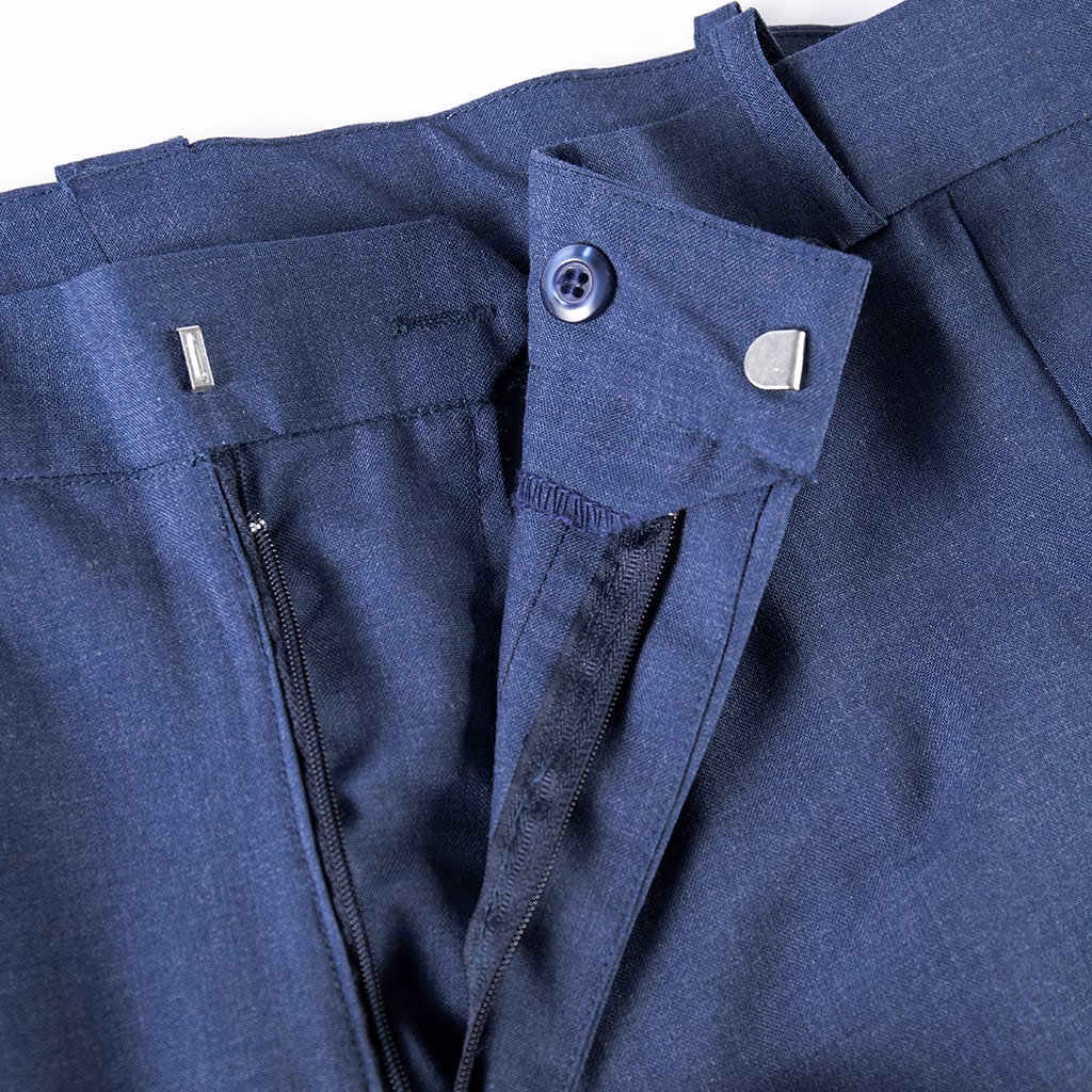 Close-up of the zip fly and button closure on the waistband of the custom navy wool blend uniform trousers.