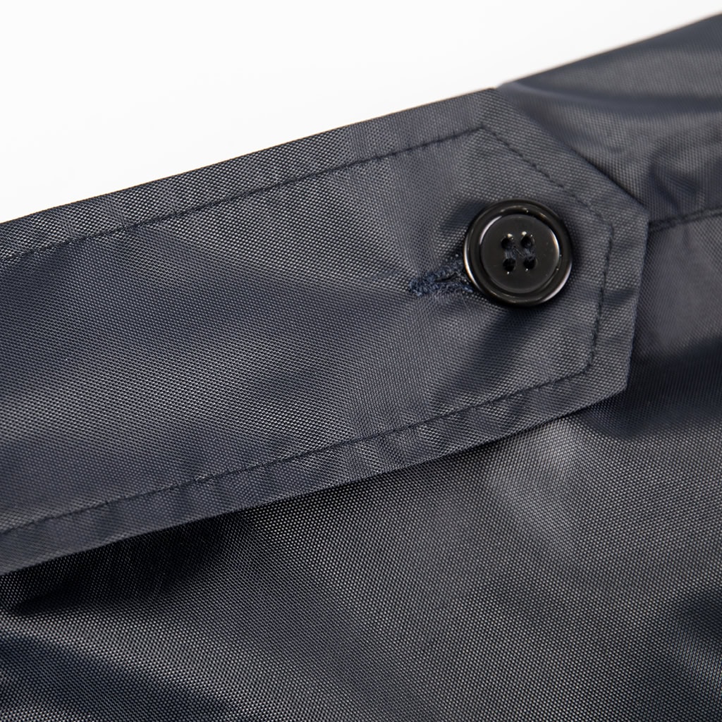 Close-up of a high-end custom button on the pocket of the navy blue waterproof trench coat.